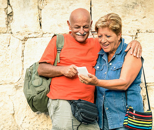 Happy older couple traveling and using smartphone