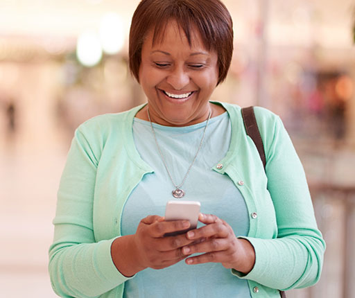 Smiling woman looking at mobile phone in mall